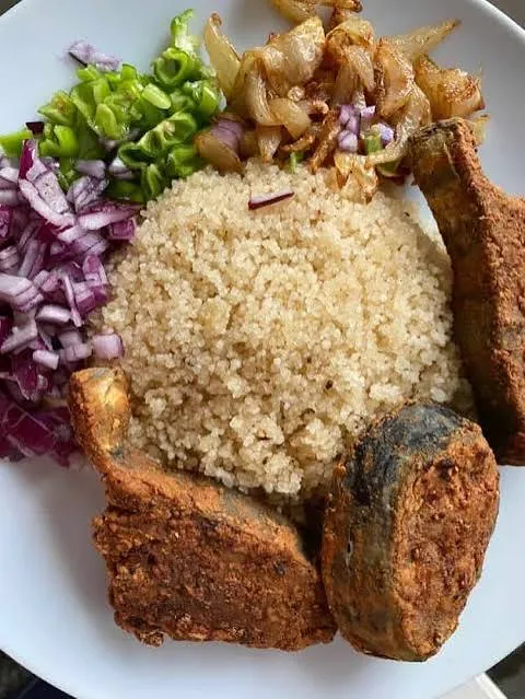 Fried fish served with couscous, onion, and green chilli