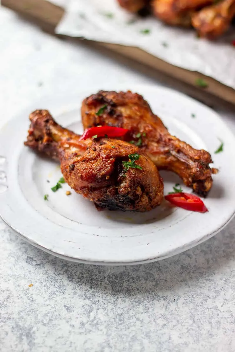 Close-up of two smoke-grilled jerk chicken drumsticks with chilli and herbs