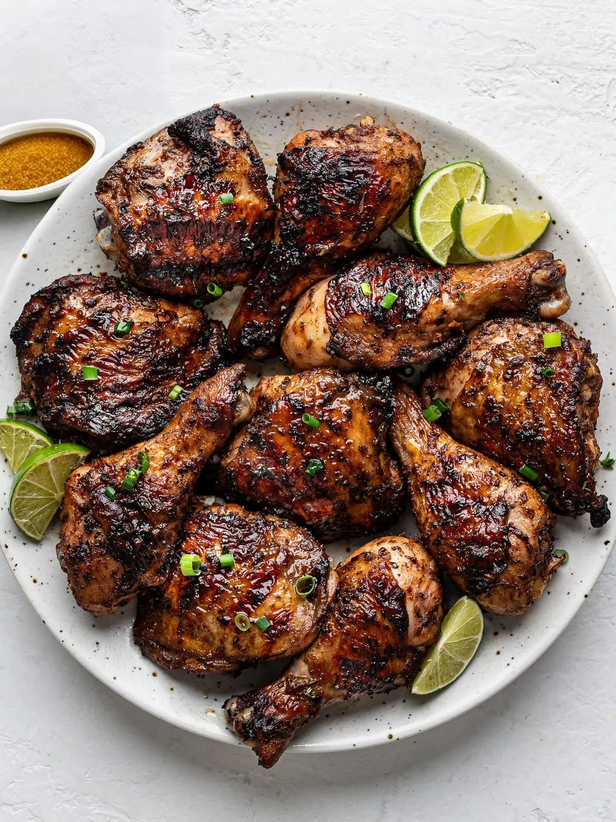 A platter of glazed, smoke-grilled jerk chicken with fresh lime